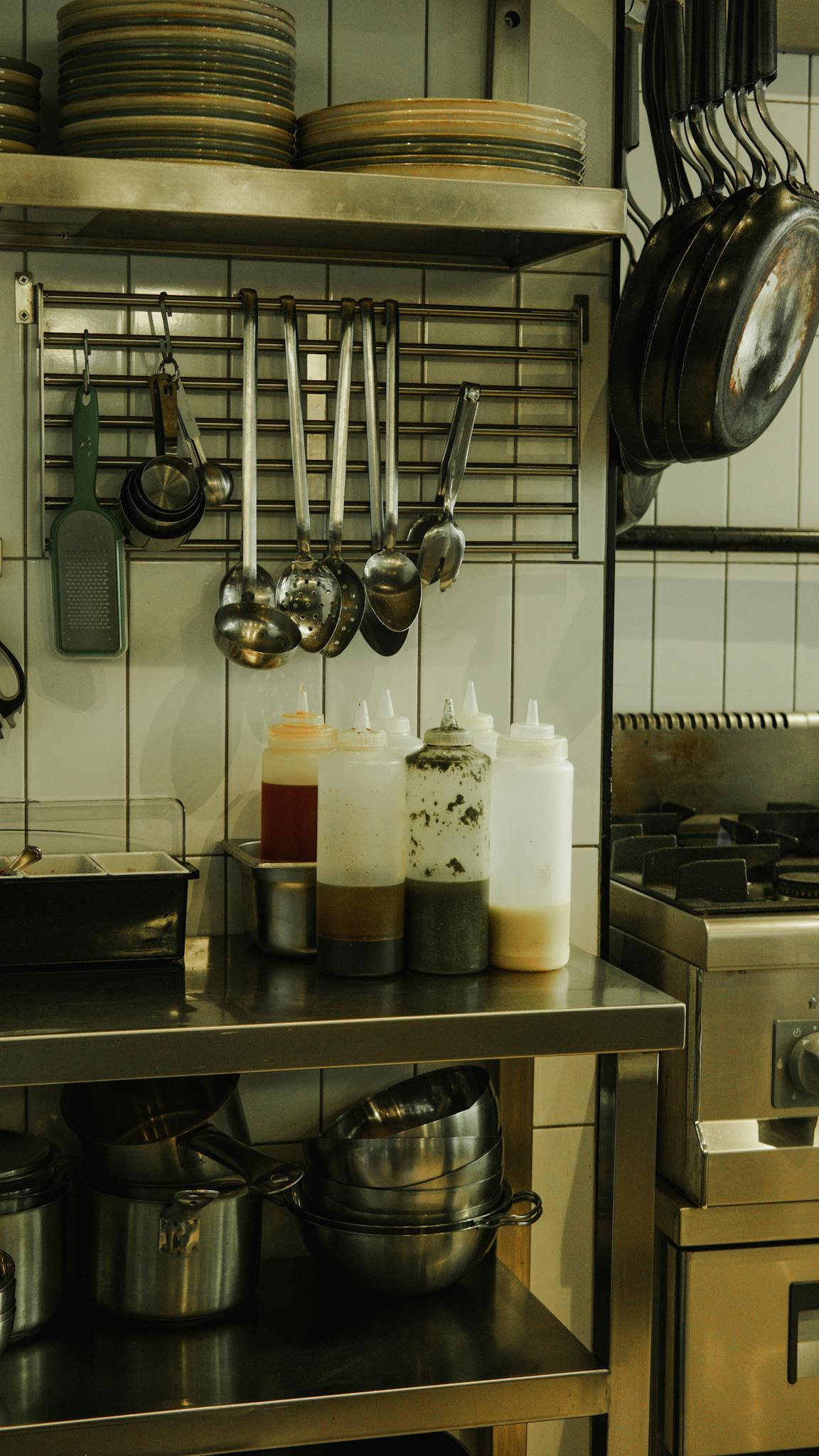 A kitchen with a stove, pots and pans and utensils