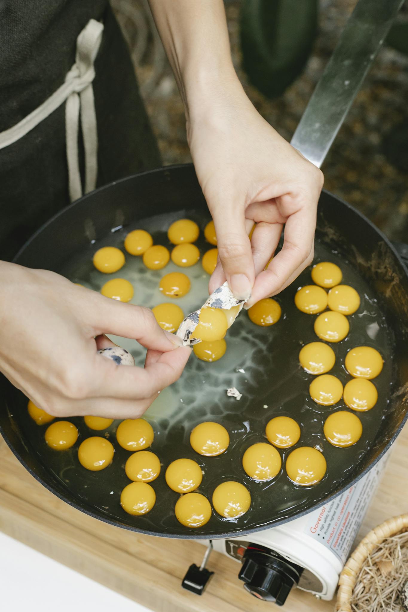 Crop woman breaking quail egg into pan